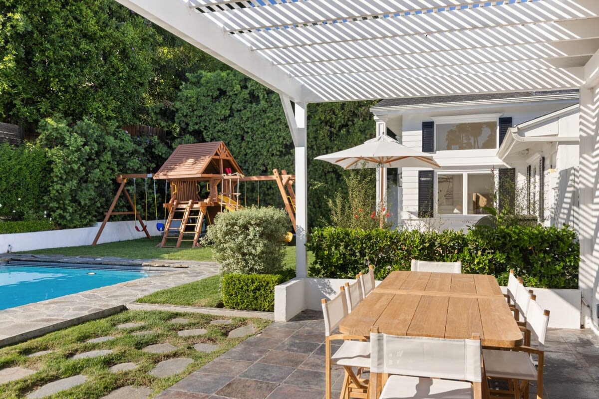 Dine alfresco by the pool on a large Teak Table, offering an inviting space for memorable meals under the Beverly Hills sky.