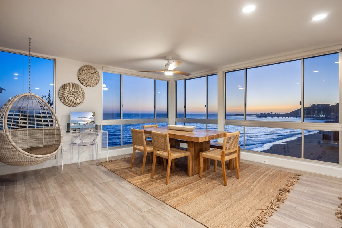 As the sun sets, the dining room transforms into a glowing oceanfront haven.