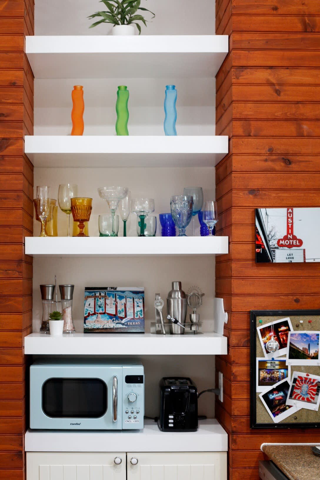 This corner of the kitchen is adorned with a vintage glassware display and a retro microwave.