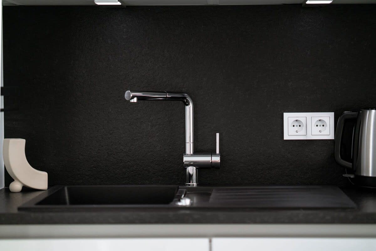 Sleek kitchenette with modern amenities and chic black backsplash for easy meal prep.