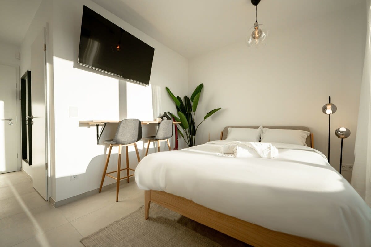 Bright and airy workspace with comfortable seating next to your bed.