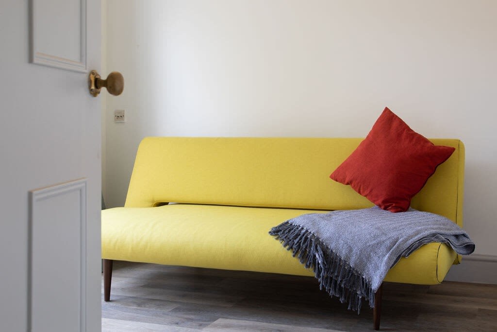 The ground floor snug has a double sofa bed in a sandy yellow.