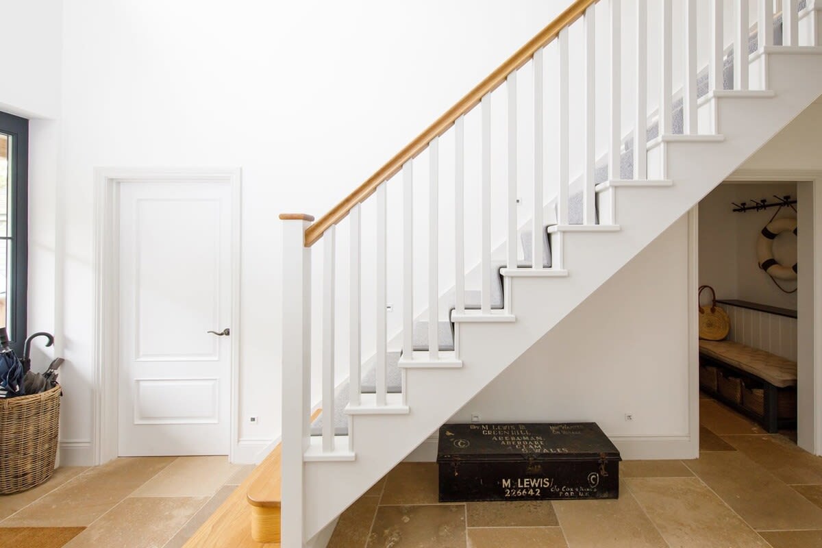 The coatroom is nestled under the staircase leading to the bedrooms