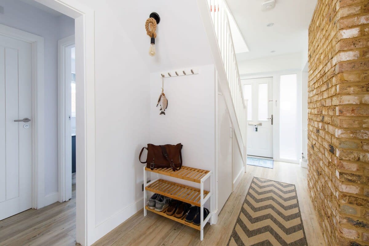 The bright and airy hallway has a shoe rack and hanging space for coats and jackets.