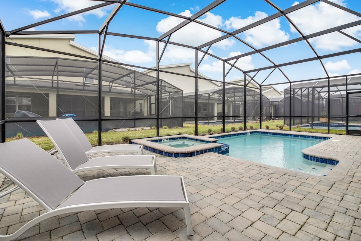 Relax in your private screened pool oasis with a hot tub and lounge chairs, perfect for soaking up the sun in comfort.