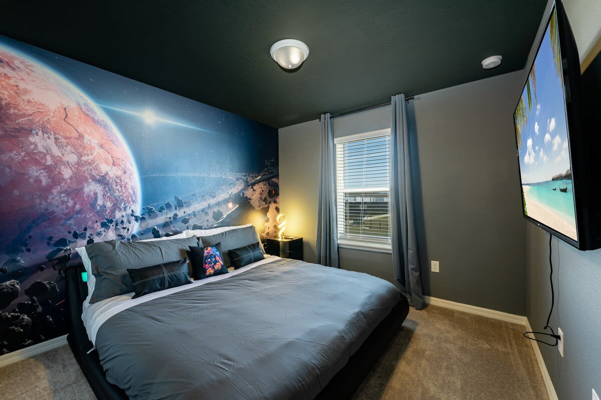 Immerse yourself in a cosmic escape with this space-themed bedroom, complete with modern comforts and a stunning mural.
