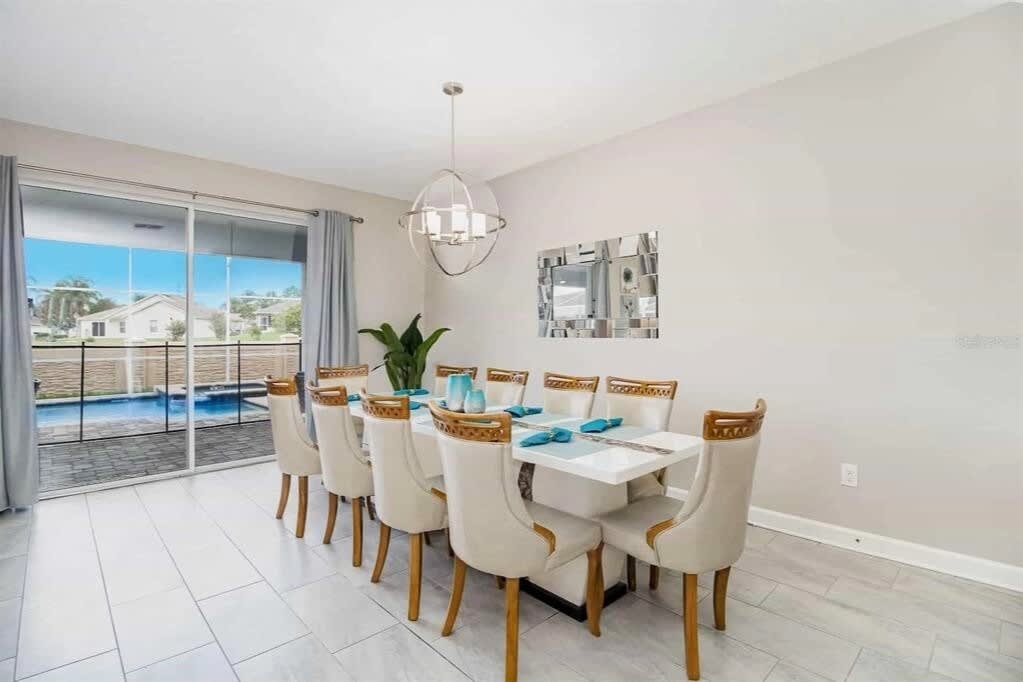 Private dining room with seating for large groups, turquoise place settings, a contemporary pendant light, and pool views through expansive sliding glass doors.