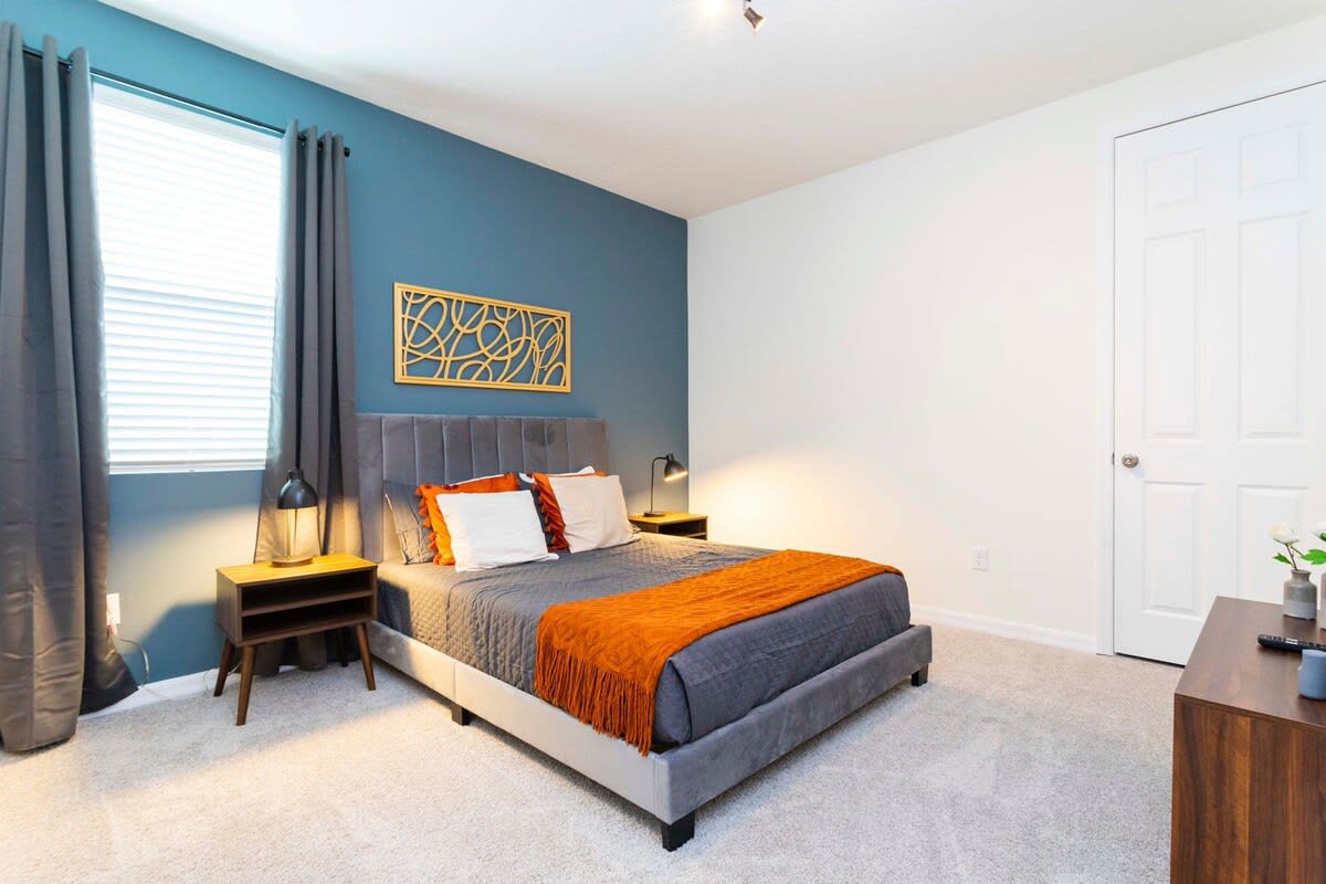 Relax in this stylish bedroom featuring a plush bed, vibrant accents, and modern decor for a cozy retreat.