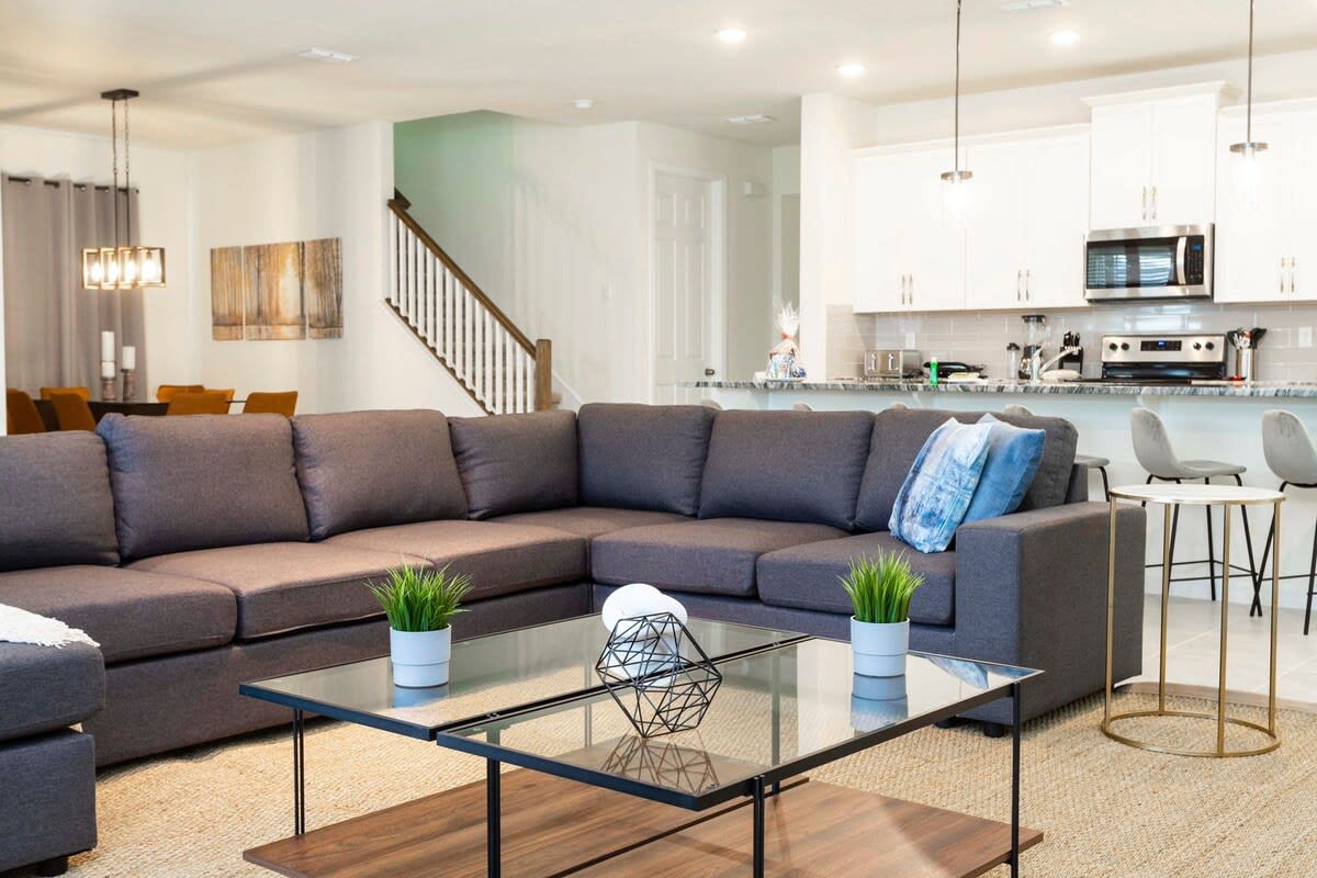 Relax in this stylish open-concept living area with a cozy sectional sofa and modern kitchen, perfect for entertaining.