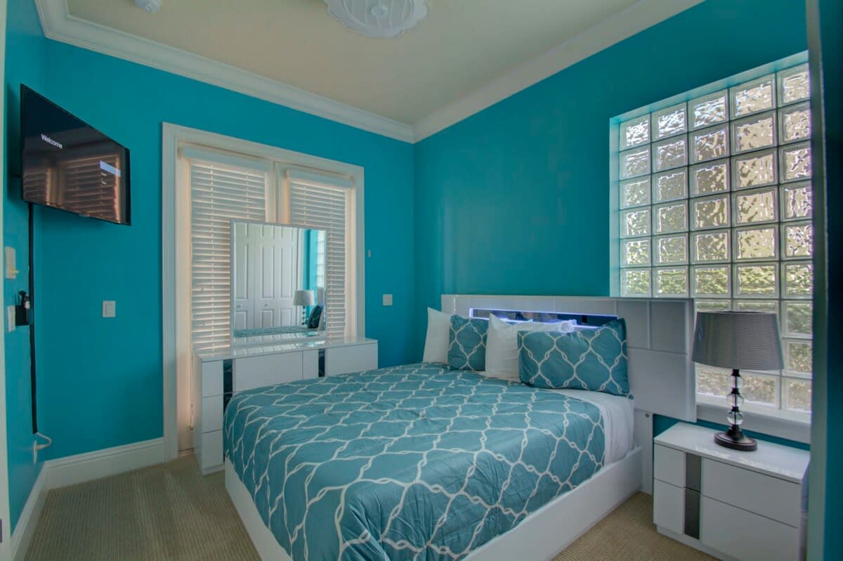 Relax in this vibrant turquoise bedroom, featuring modern furnishings and a cozy atmosphere for a perfect getaway.