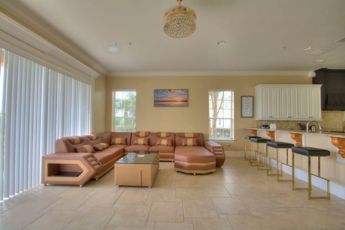 Relax in this spacious living room featuring a unique sectional sofa and bar seating, perfect for family gatherings and enjoying natural light.