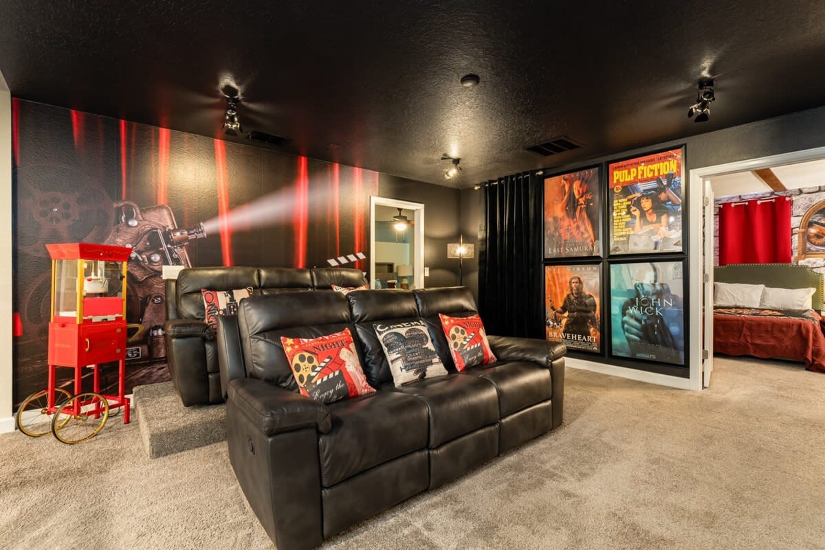 Enjoy a cinematic experience in your private home theater with plush recliners, iconic movie posters, and a classic popcorn machine.