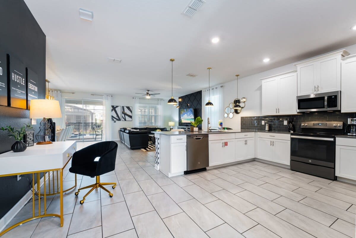 Open-concept kitchen with a generous island, stainless-steel appliances, pendant lighting, and a connected living area for group meals and relaxed gatherings.