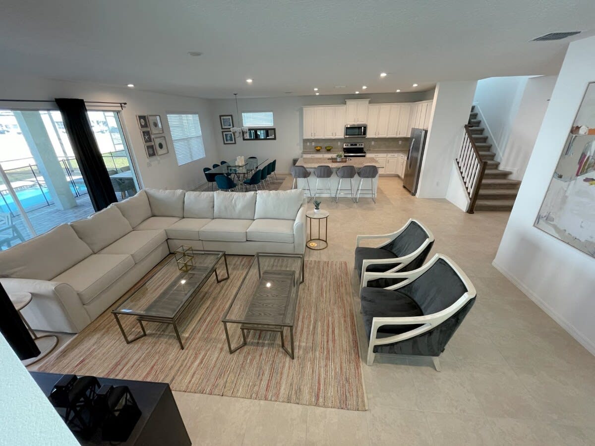 Elegant open-plan living area with cozy seating, modern kitchen, and poolside views, ideal for gatherings and relaxation.