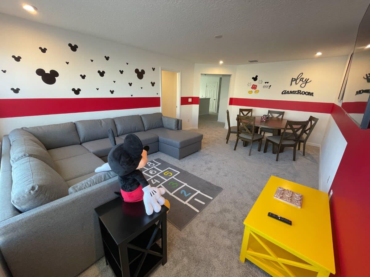 Dive into fun in this Mickey Mouse-themed game room with cozy seating and playful decor, perfect for family gatherings.