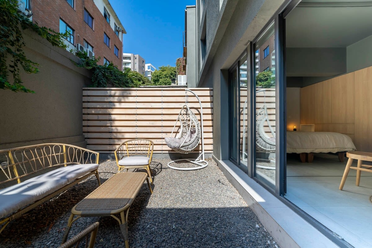 Relax in your private patio oasis with cozy seating and a hanging chair, perfect for enjoying sunny days.