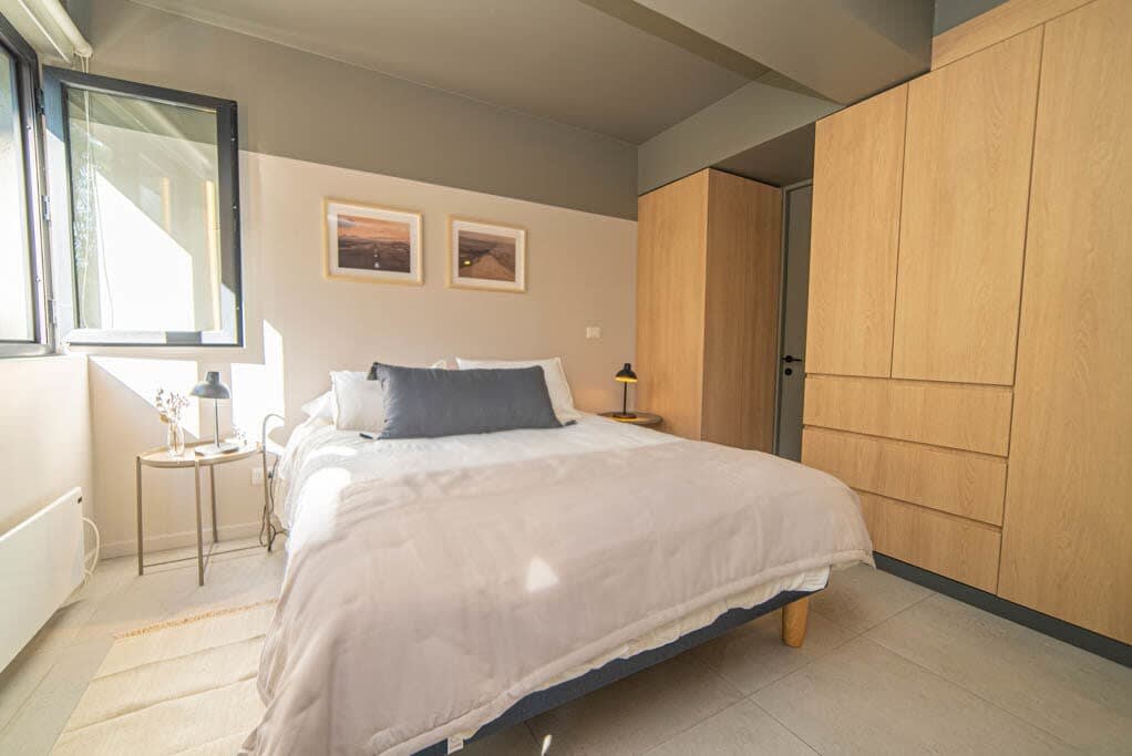 Cozy and sunlit bedroom with modern furnishings and ample storage, perfect for a relaxing stay.