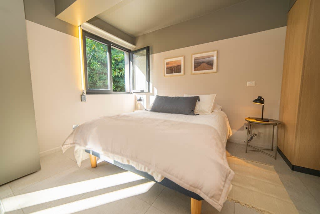Cozy and bright bedroom with a view of lush greenery, perfect for a relaxing stay.