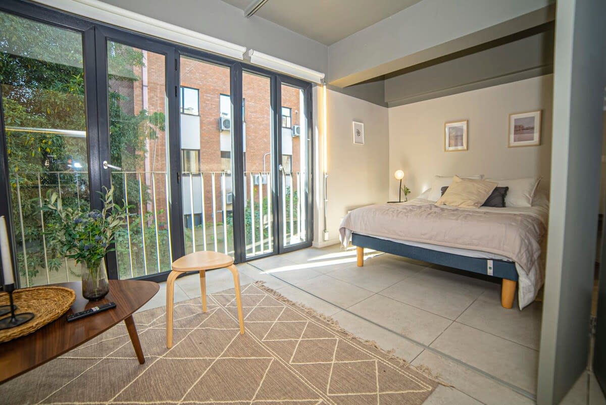 Bright and airy studio with large windows and cozy decor, perfect for a relaxing stay.