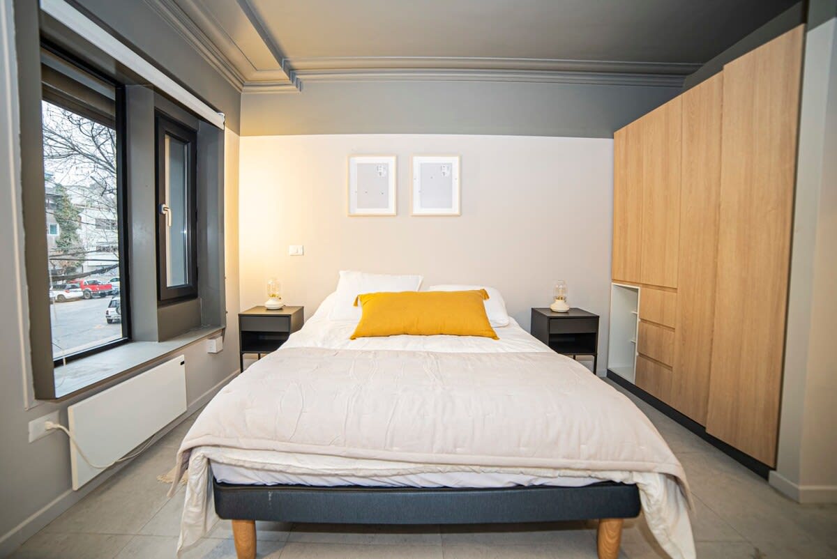 Cozy bedroom with a plush queen bed, ample natural light, and stylish modern decor for a restful stay.