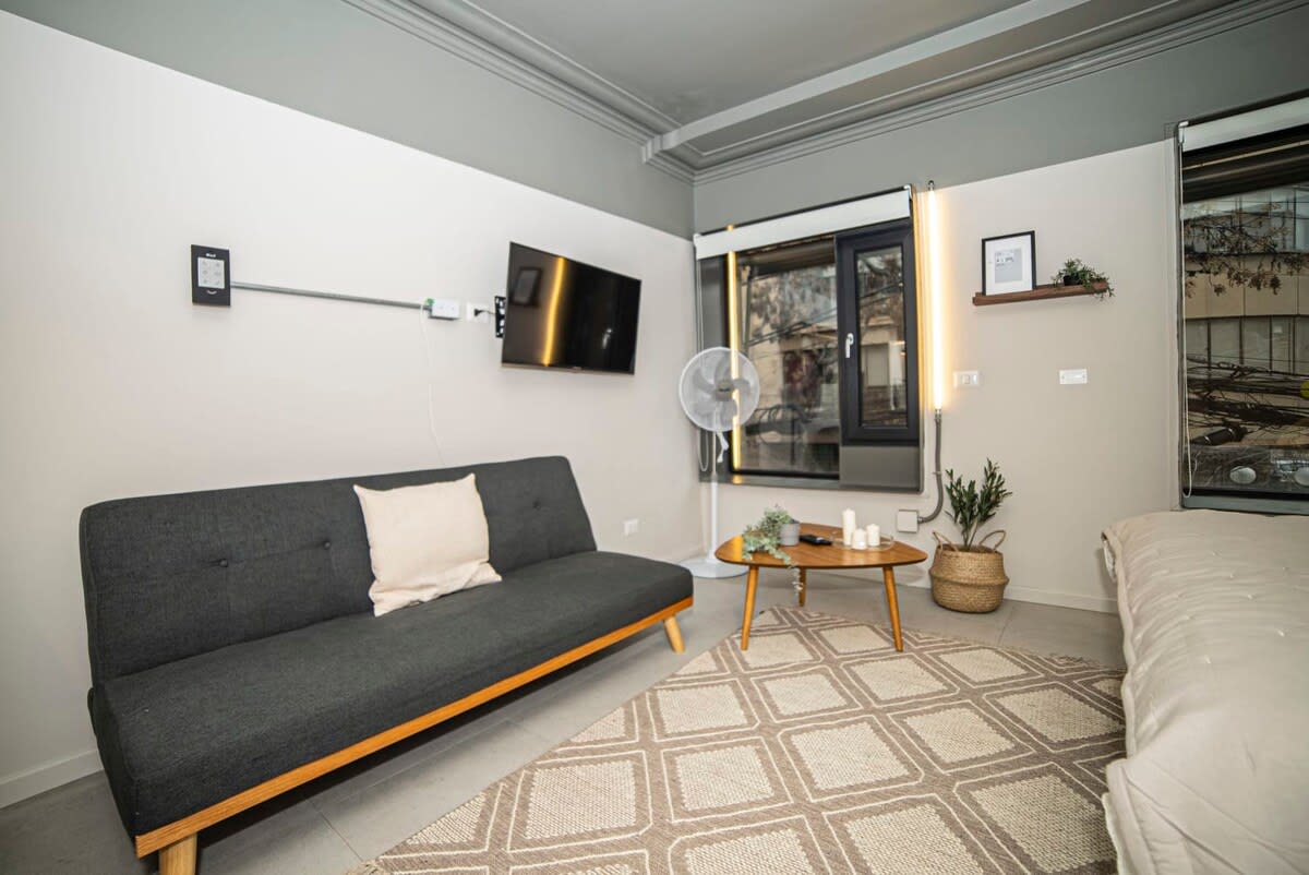 Cozy and modern living space with a sleek sofa, stylish decor, and ample natural light, perfect for relaxation and entertainment.