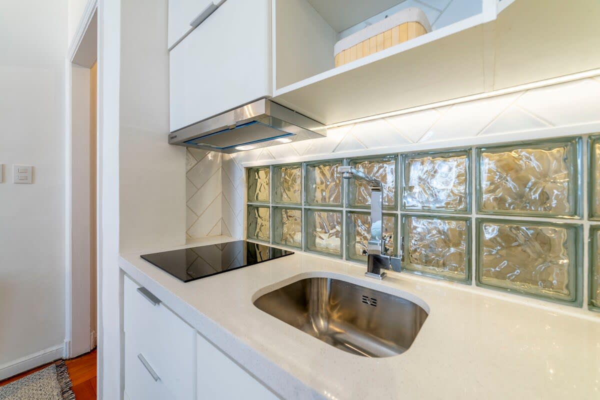 Modern kitchen with stylish glass tile backsplash and induction cooktop, perfect for cozy meals.