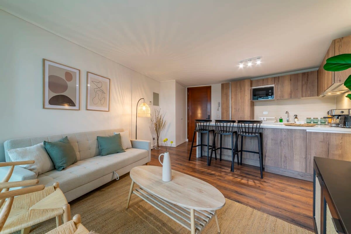 Experience modern comfort in this stylish open-concept living area with a cozy sofa, chic kitchen, and inviting decor—perfect for relaxation and entertaining.