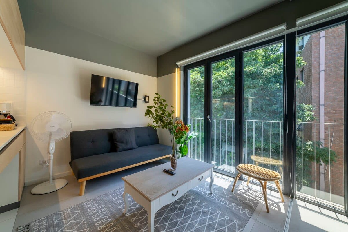 Cozy living area with abundant natural light and a view of lush greenery, perfect for relaxation.