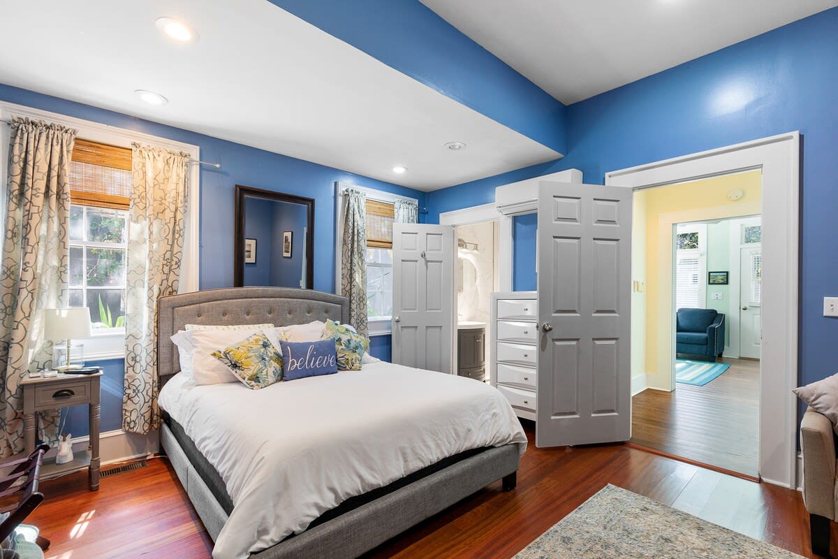 A wide view of a bedroom with a bed, nightstand, and doorway