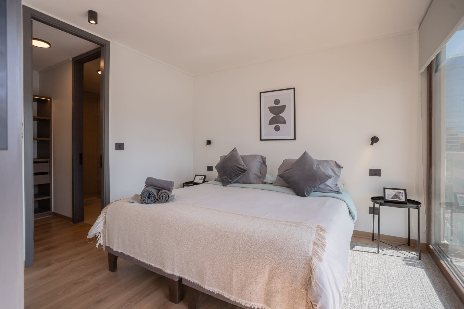 Relax in this serene bedroom with a cozy bed and stunning city views through expansive windows.