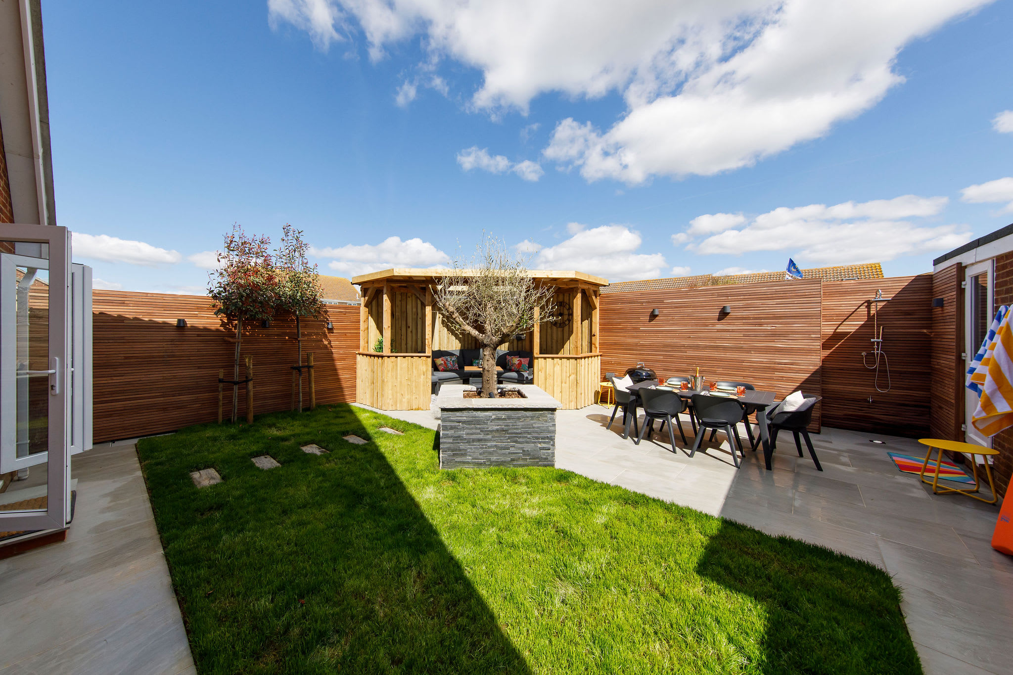 There is a lawned area, patio with dining furniture and beautiful pergola seating area.