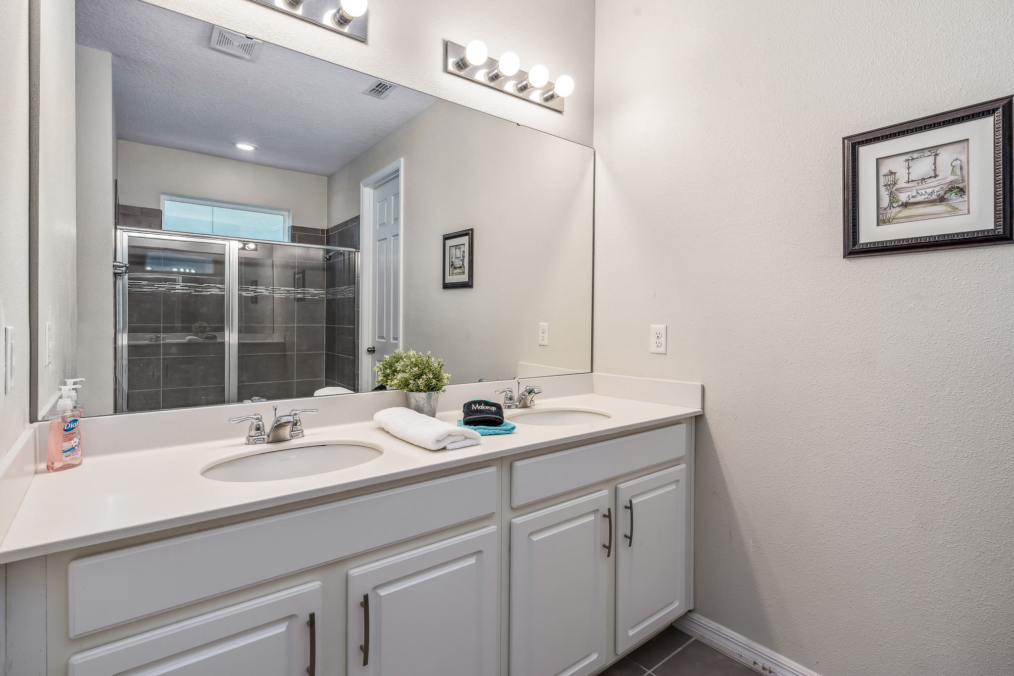 Bathroom vanity w/ ample counter space and large mirror.
