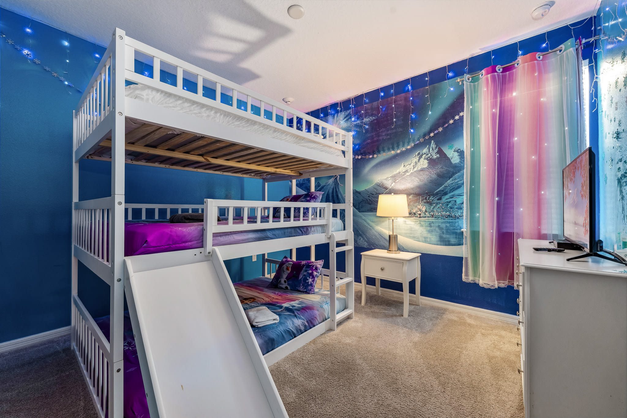 Colorful bunk room w/ playful lighting and space for kids to hang out.