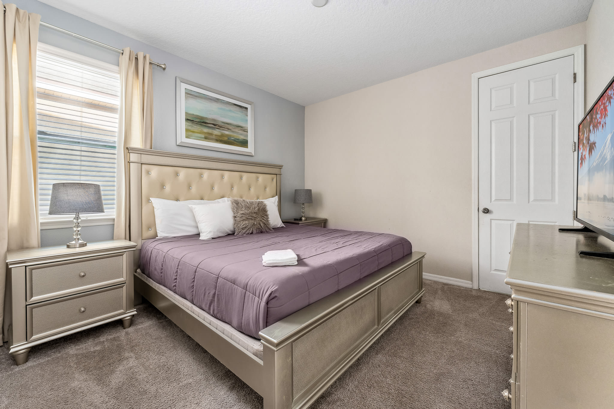 Simple bedroom w/ soft purple bedding and natural light.
