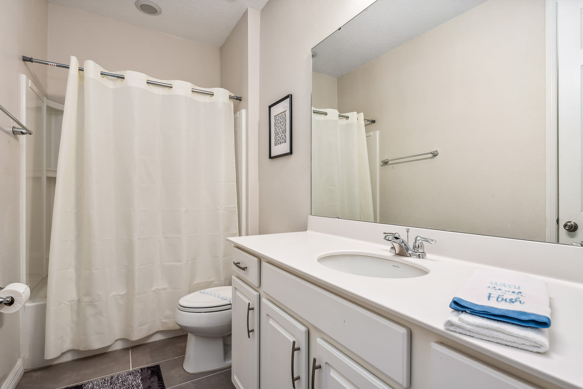 Bathroom w/ tub & shower combo and a clean, bright vanity area.