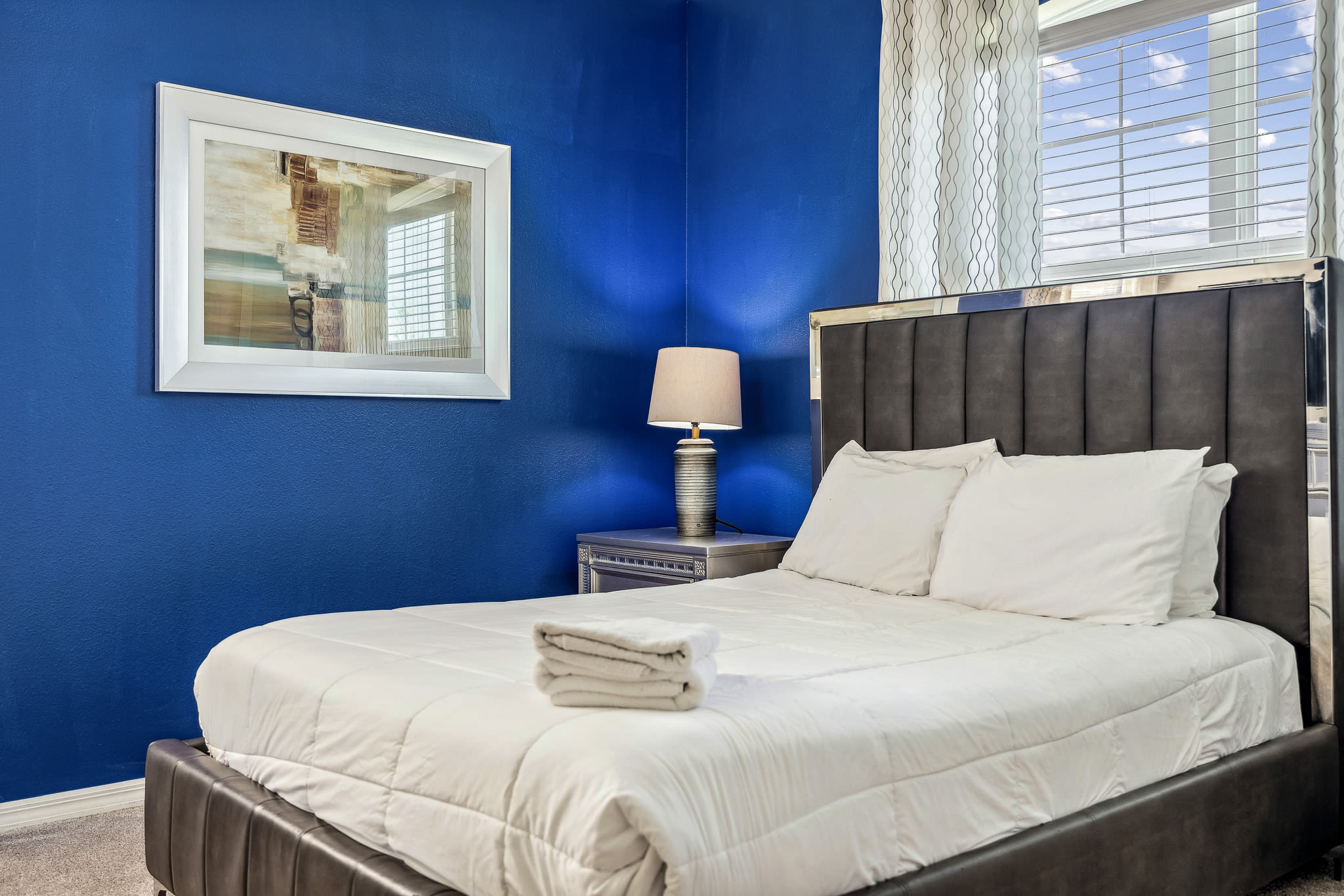 Stylish bedroom w/ blue accent wall and cozy seating for relaxing evenings.