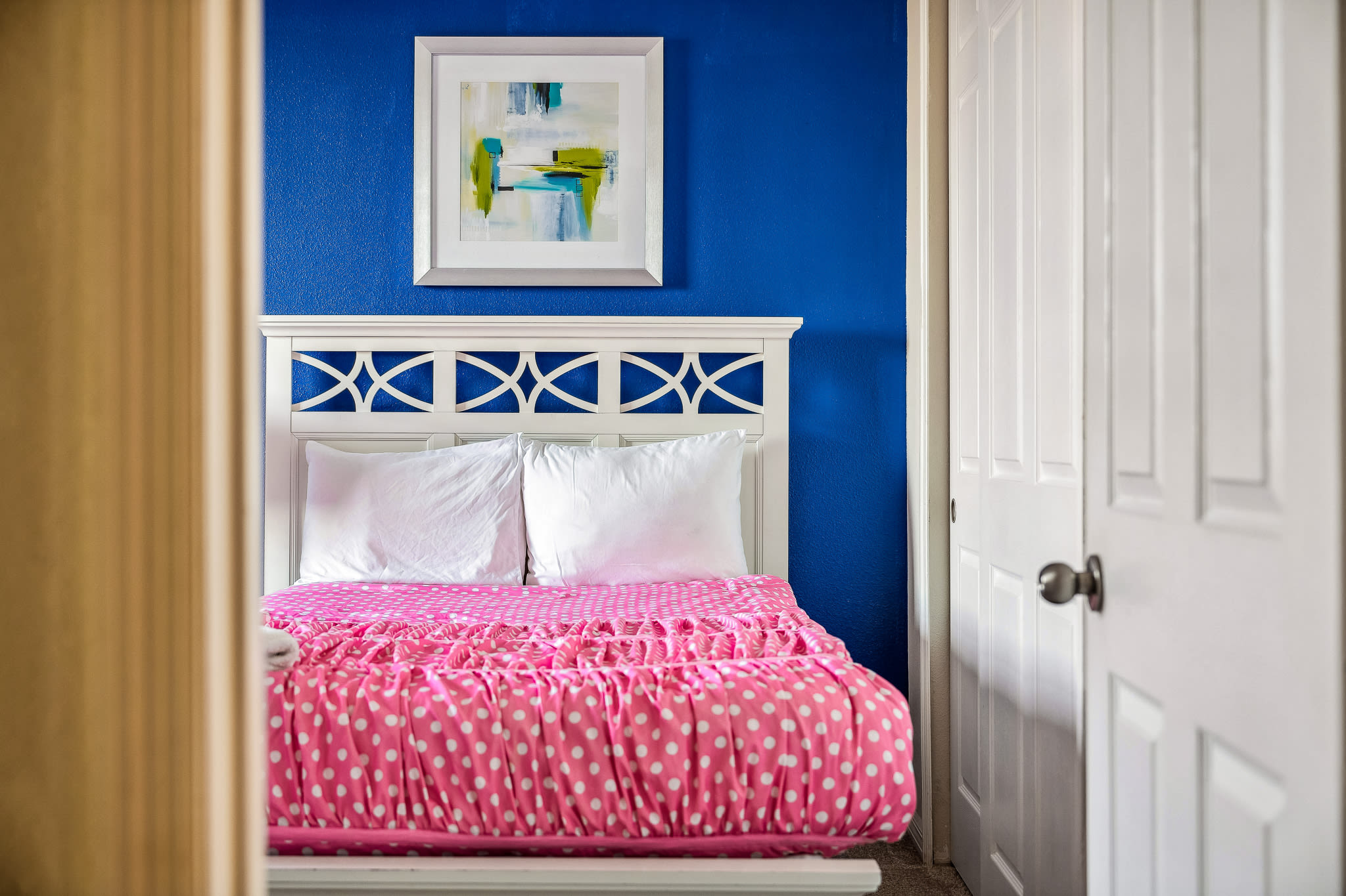 Cheerful kids’ bedroom w/ pink bedding and bright accents.