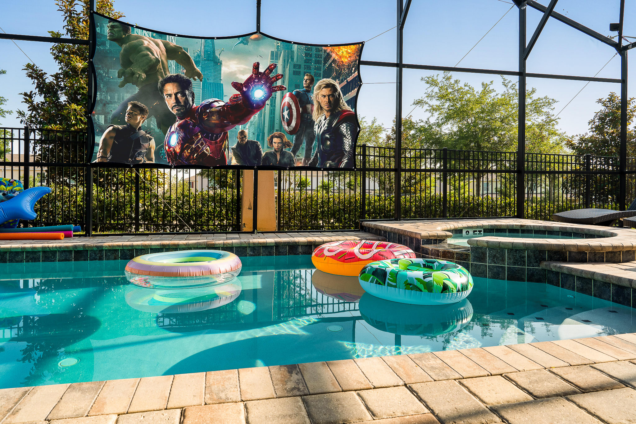 Sunlit pool w/ floaties inside a screened enclosure for all-day enjoyment.