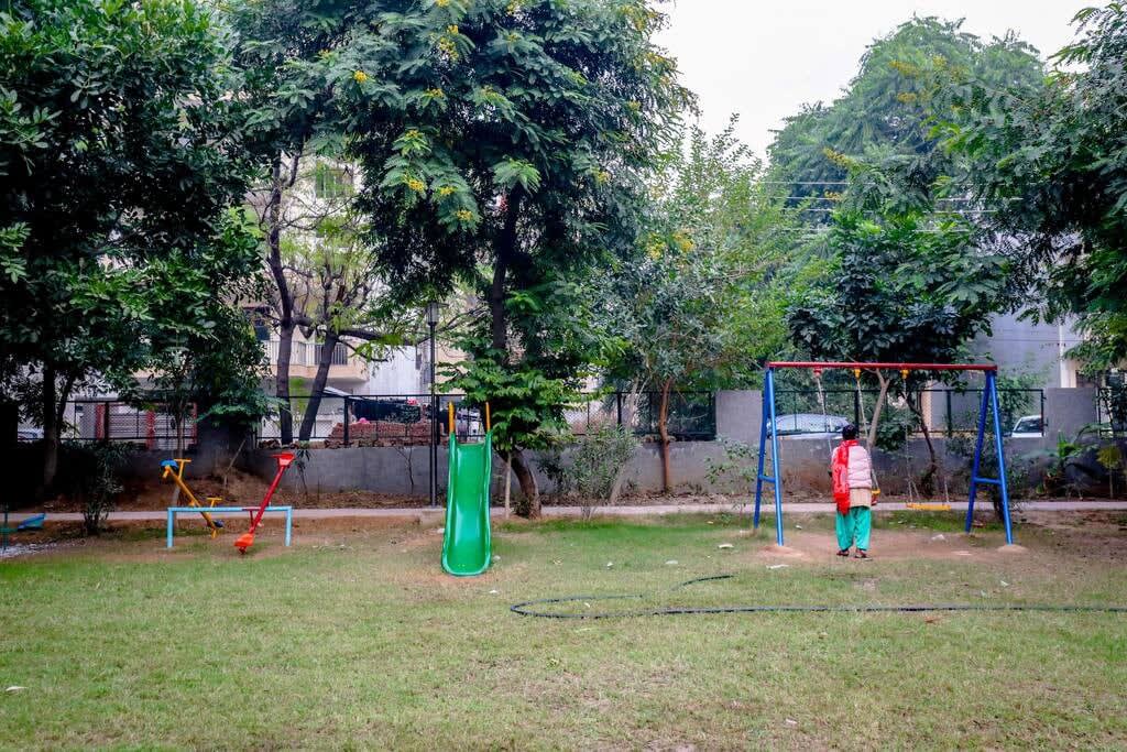 A vibrant park scene featuring children enjoying rides and games, with colorful play equipment and joyful laughter filling the air -parfait street