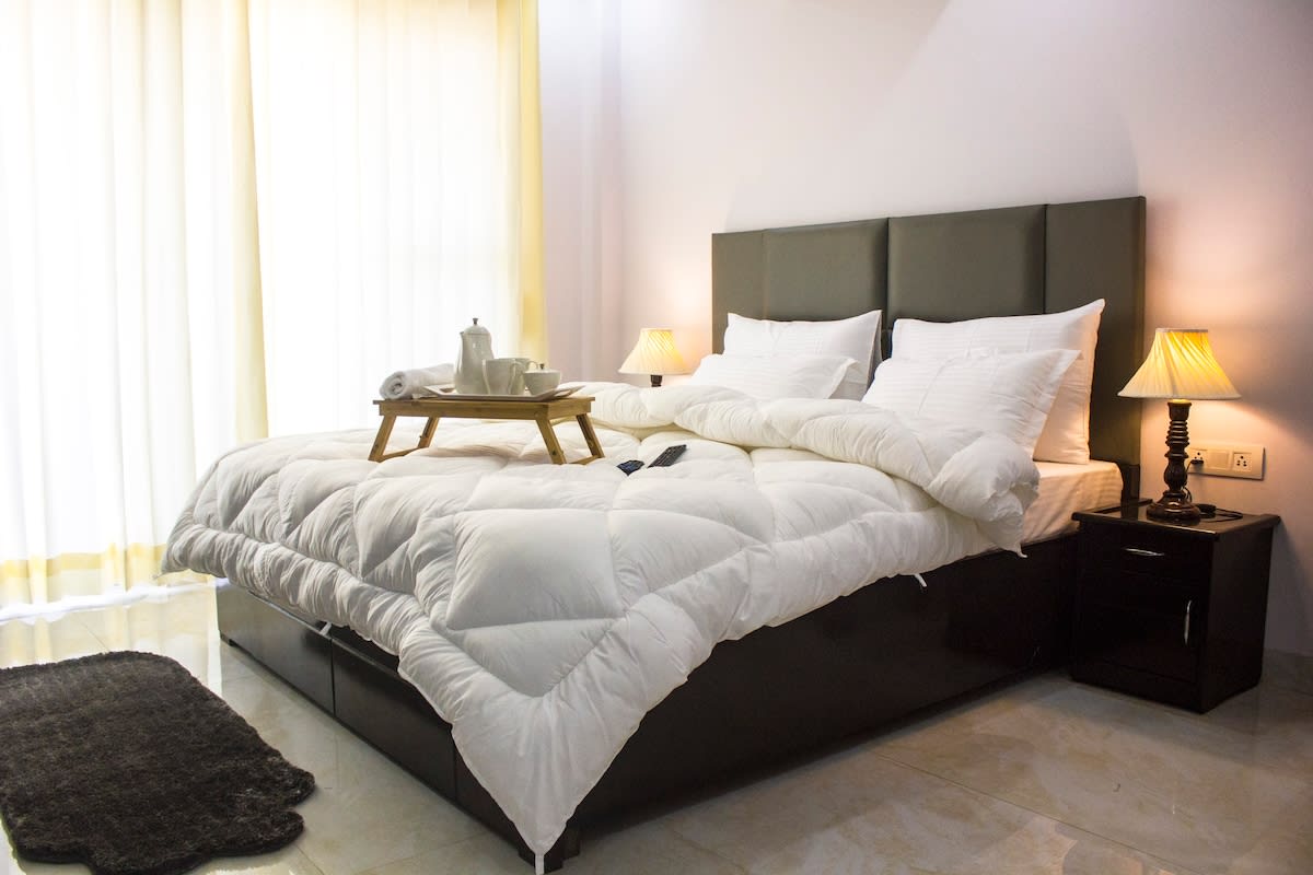 An image of a warm and inviting bedroom scenario with a cup of tea on the bedside table 