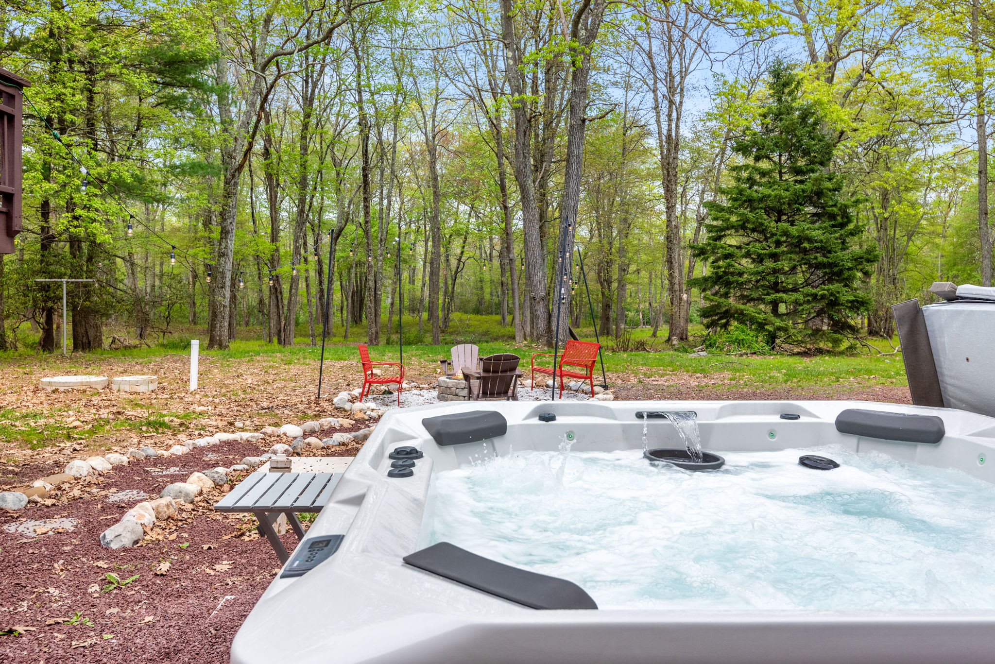 A spacious outdoor hot tub with a beautiful wooded backdrop, ideal for soaking and unwinding in nature.