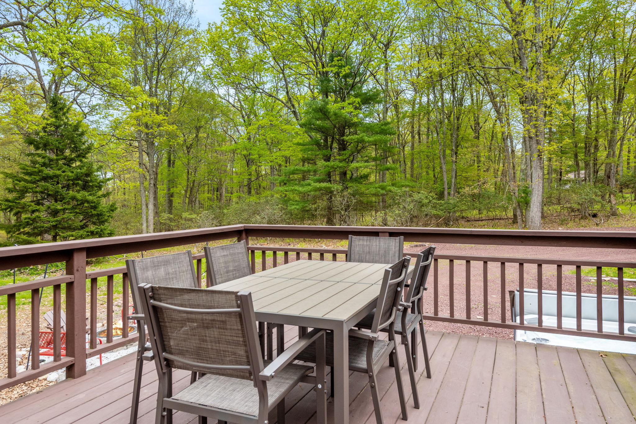 A spacious deck with a dining table set against a backdrop of towering trees, creating the perfect outdoor dining experience.