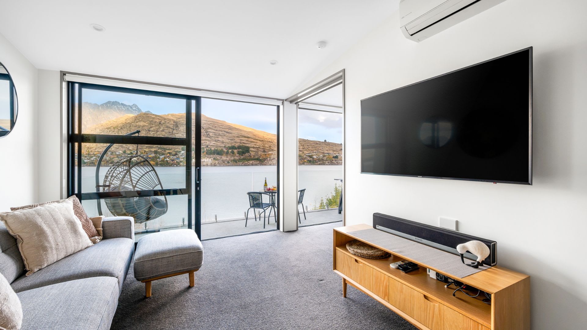 Modern Living Room with Entertainment and Scenic Beauty – This chic living room boasts a flat-screen TV and an incredible view of the lake and mountains, providing the perfect backdrop for movie nights or cozy gatherings with friends and family.