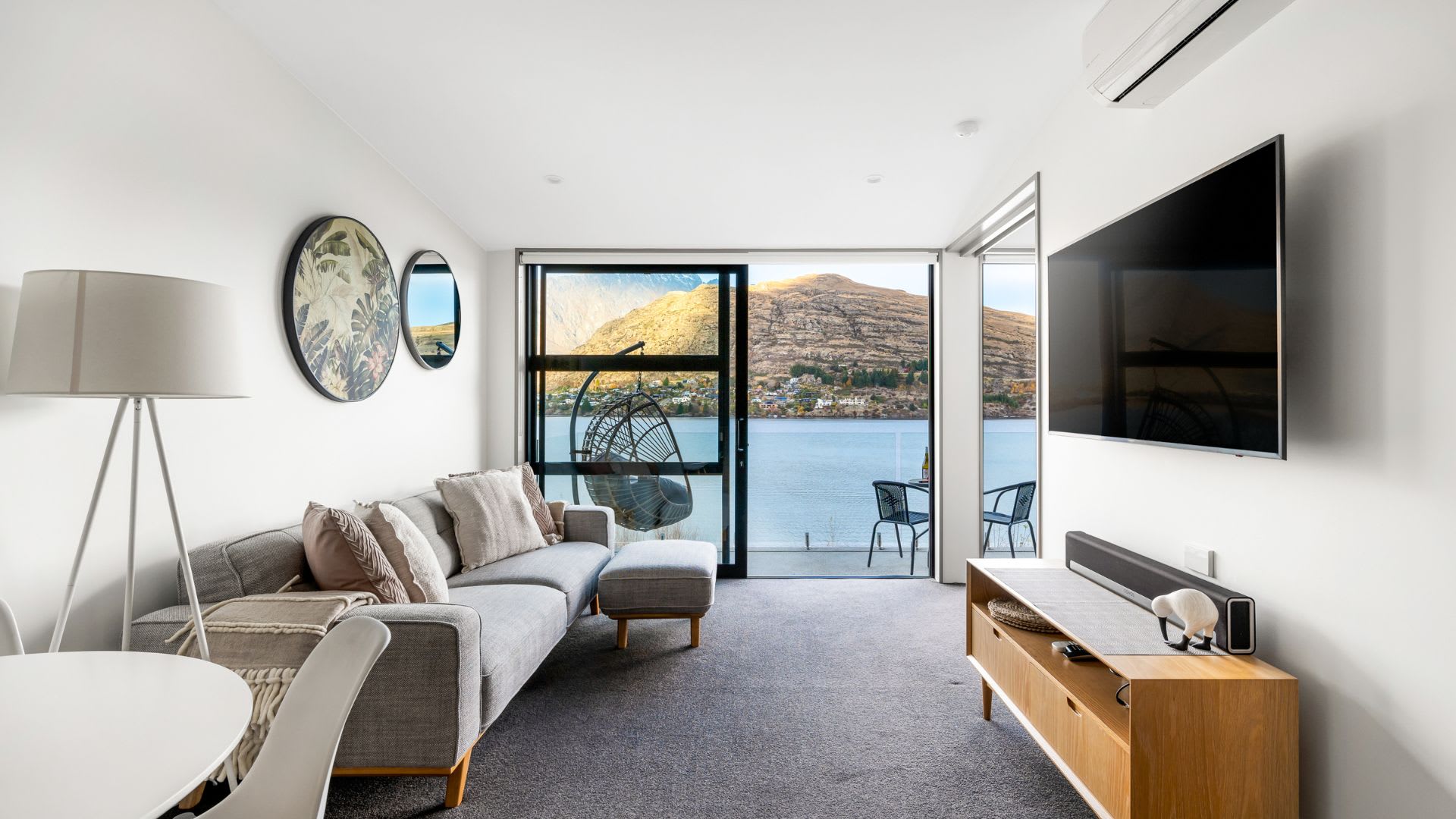 Elegant Living Space with Flat-Screen TV and Gorgeous Backdrop – Enjoy the best of both worlds in this stylish living room, complete with a large flat-screen TV and breathtaking views of the lake and mountains.