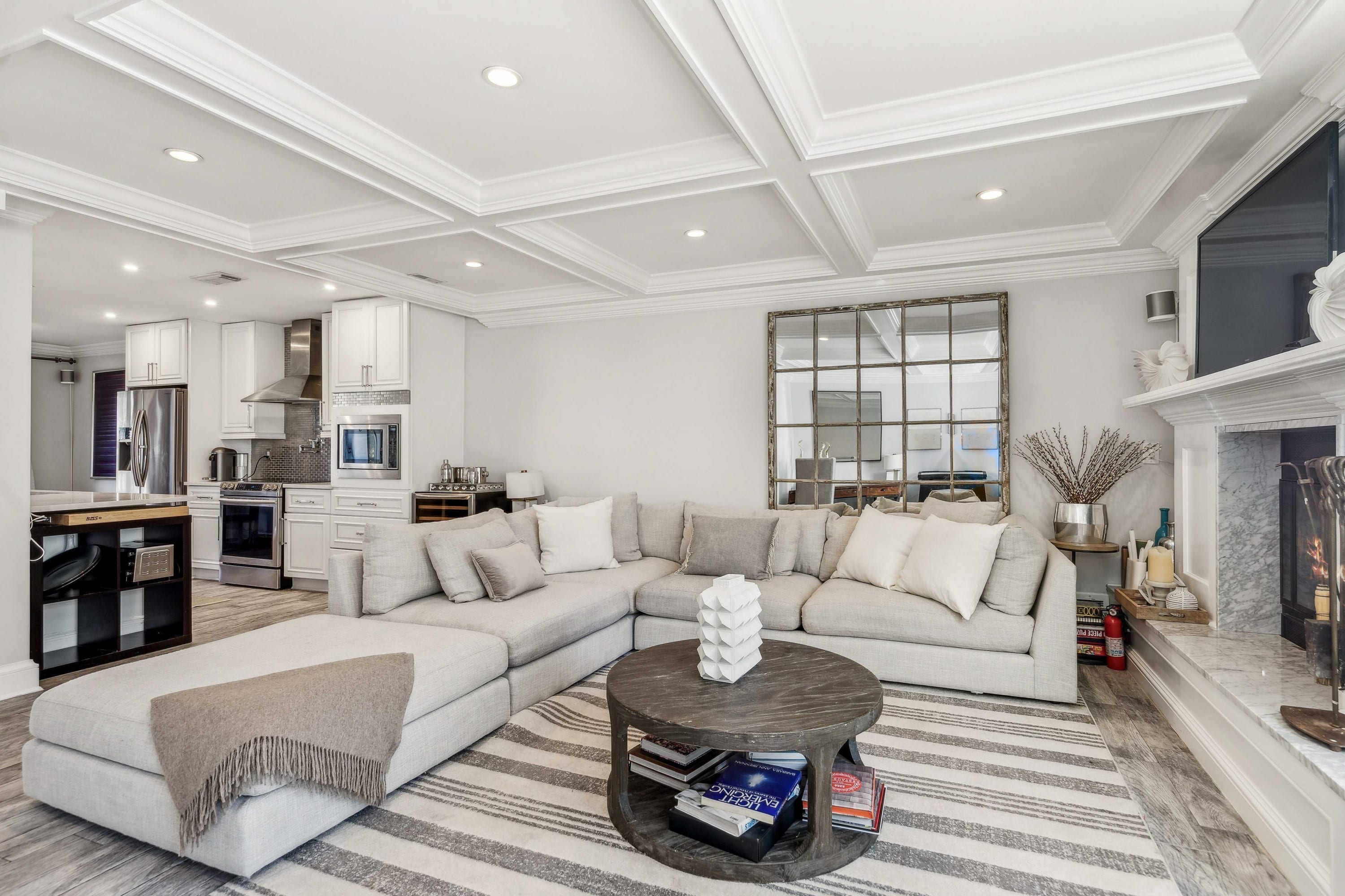 Open-plan living room and kitchen with a gray sectional, round coffee table, and fireplace.