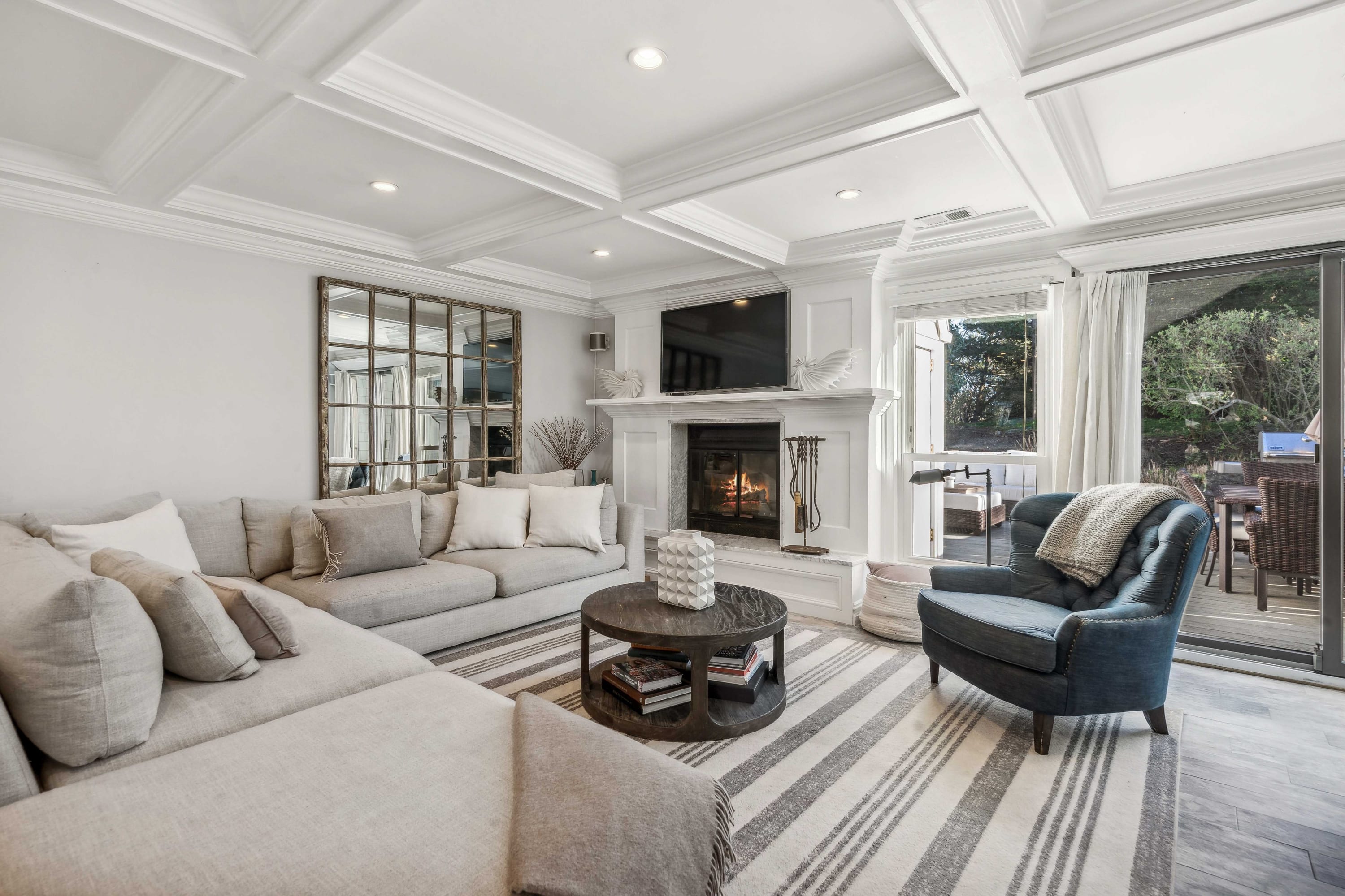 Living room with a gray sectional, blue accent armchair, fireplace, and French doors to the deck.