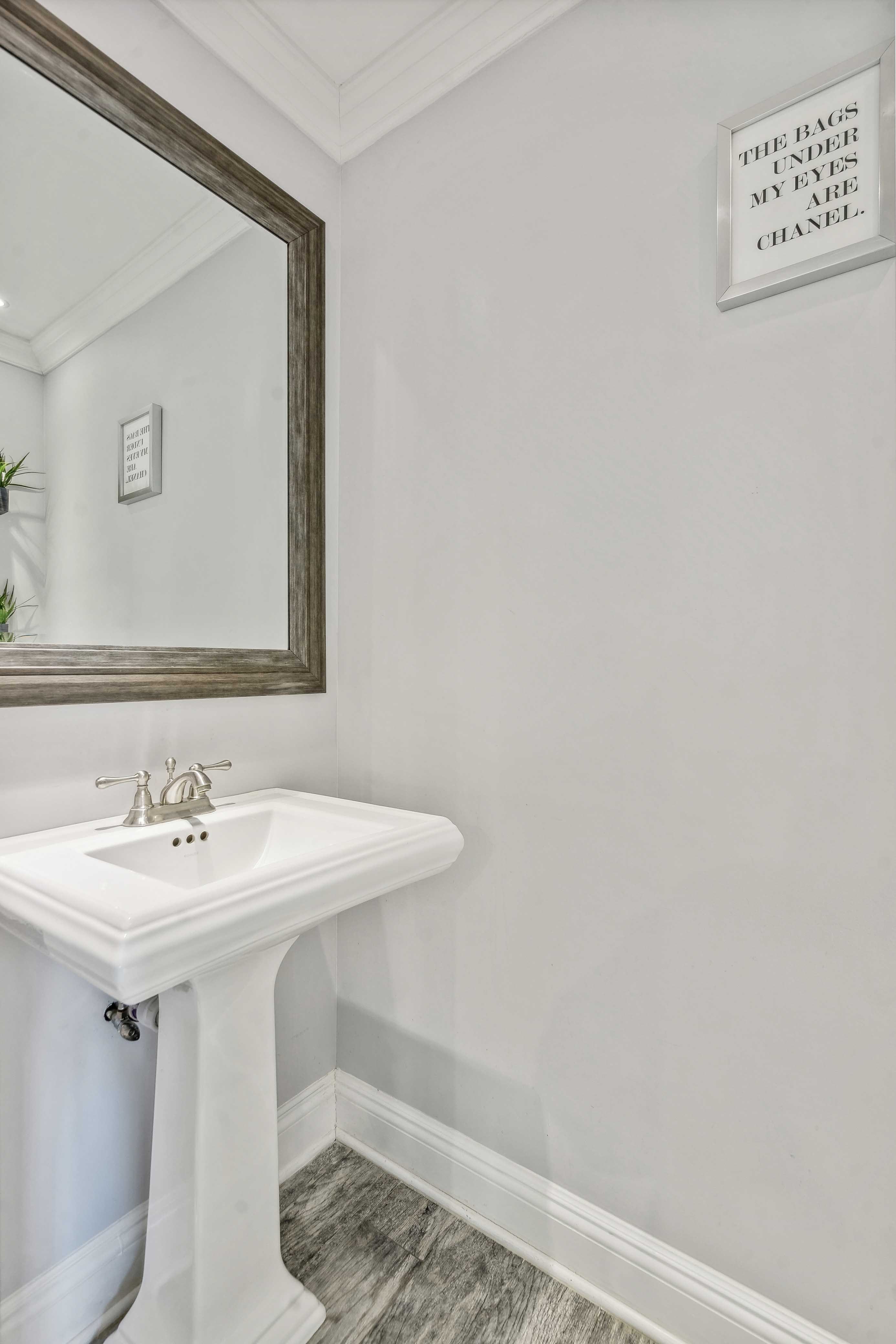 Powder room with a pedestal sink and framed wall art.