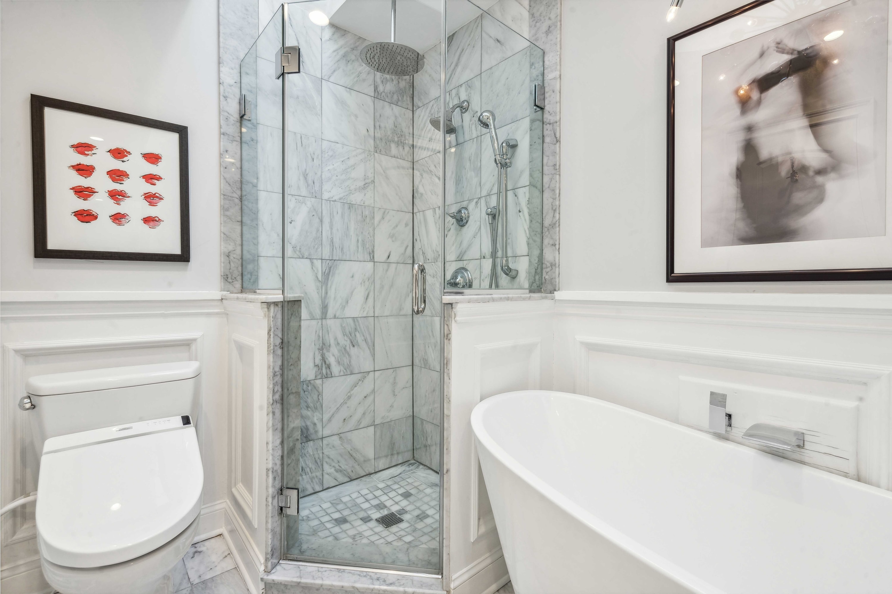 Bathroom with a glass-enclosed shower, freestanding soaking tub, and framed art.