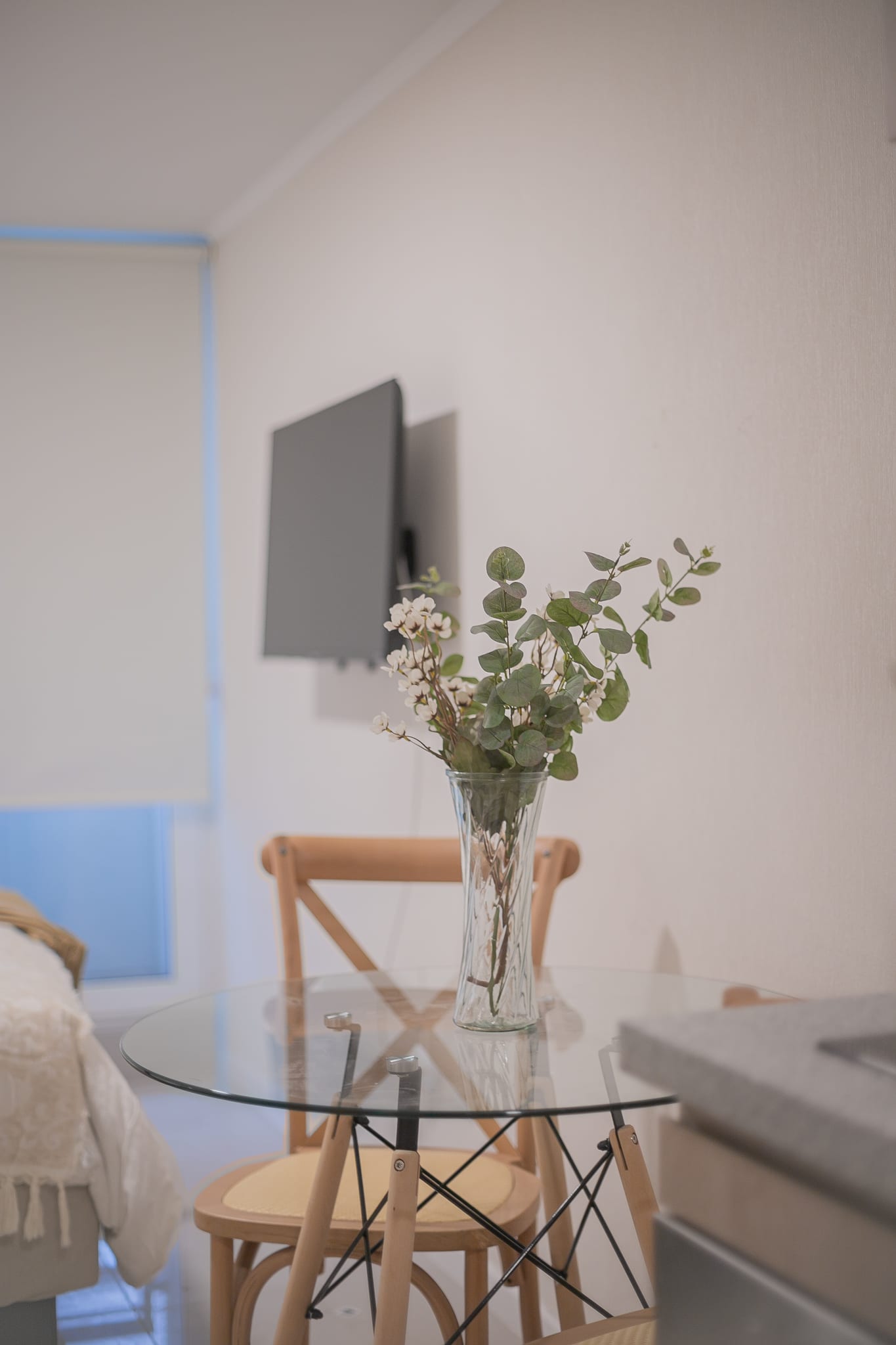 Cozy dining nook with elegant glass table and floral decor, perfect for intimate meals.