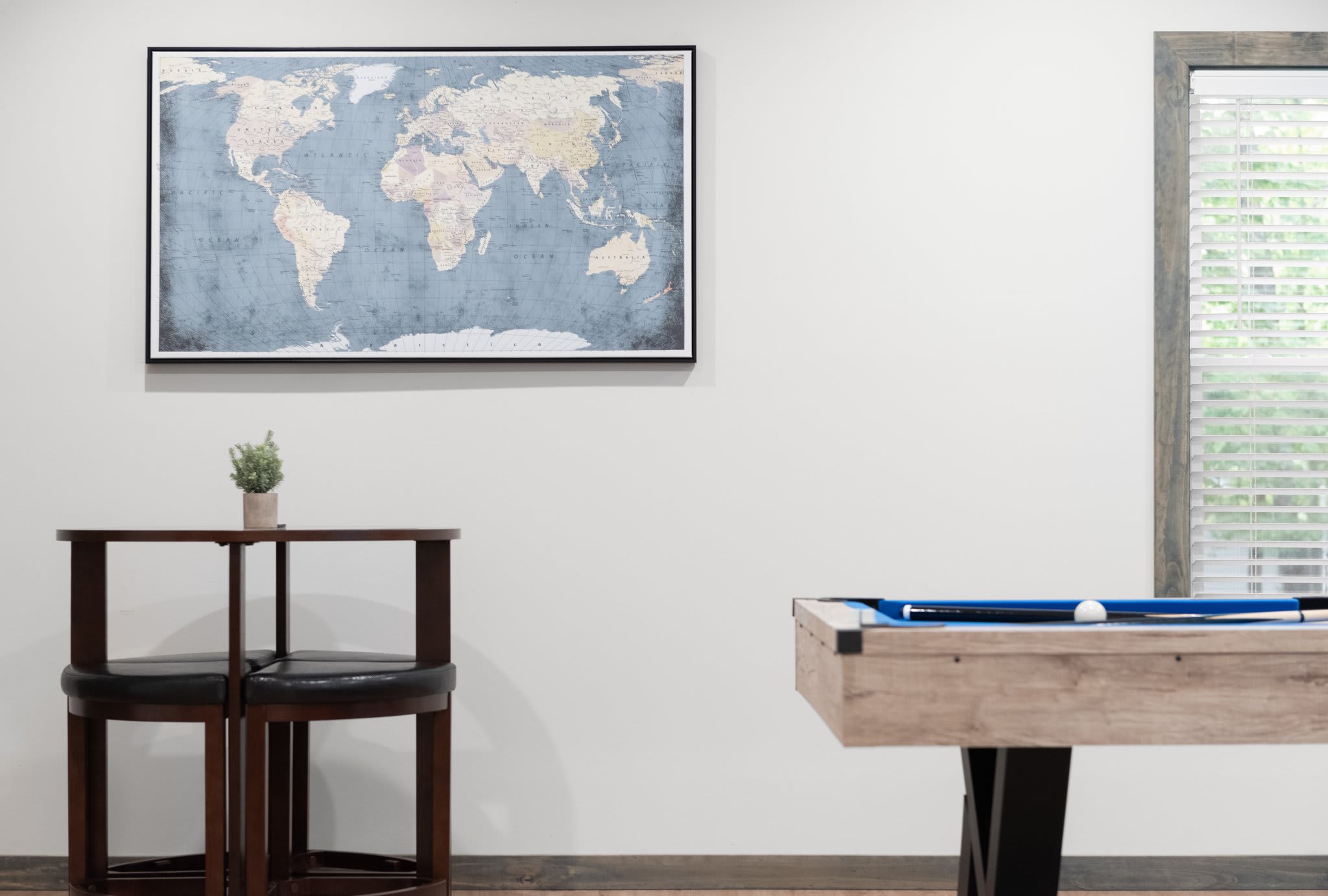 A bright, welcoming game space with a world map on the wall, perfect for some friendly pool competition or just kicking back with a drink.